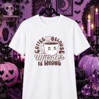 A white short-sleeve graphic T-shirt hanging on a black hanger against a Halloween-themed purple background with pumpkins, candles, and gothic decor. The shirt features a cartoon coffee cup with a smiling face and the text 'COFFEE BECAUSE Murder IS WRONG' in brown and pink.
