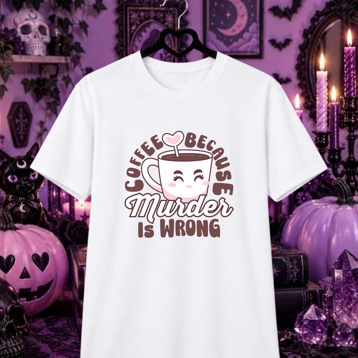 A white short-sleeve graphic T-shirt hanging on a black hanger against a Halloween-themed purple background with pumpkins, candles, and gothic decor. The shirt features a cartoon coffee cup with a smiling face and the text 'COFFEE BECAUSE Murder IS WRONG' in brown and pink.