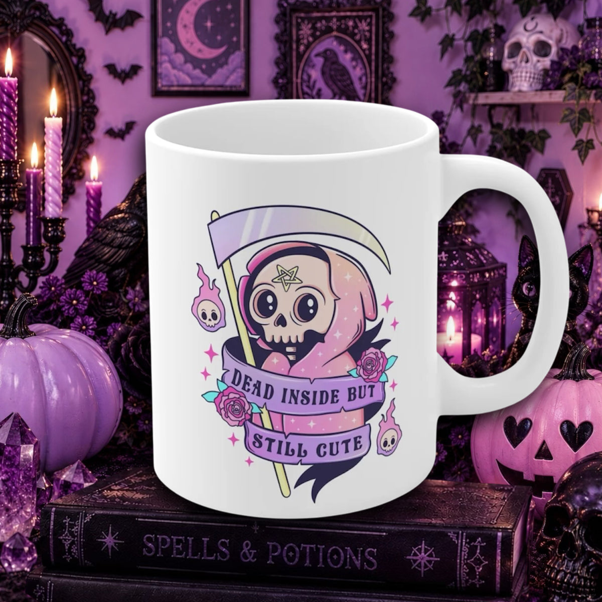 A white ceramic mug with a gothic cartoon grim reaper design, displayed on a book surrounded by Halloween decorations like pumpkins, candles, and a skull in a purple themed setting.