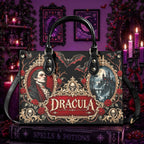 A black handbag with gothic Dracula artwork, featuring ornate gold filigree, red roses, skull motifs, and a central 'DRACULA' title panel. The bag is displayed on a book in a dark, purple-themed room with candles and framed art.