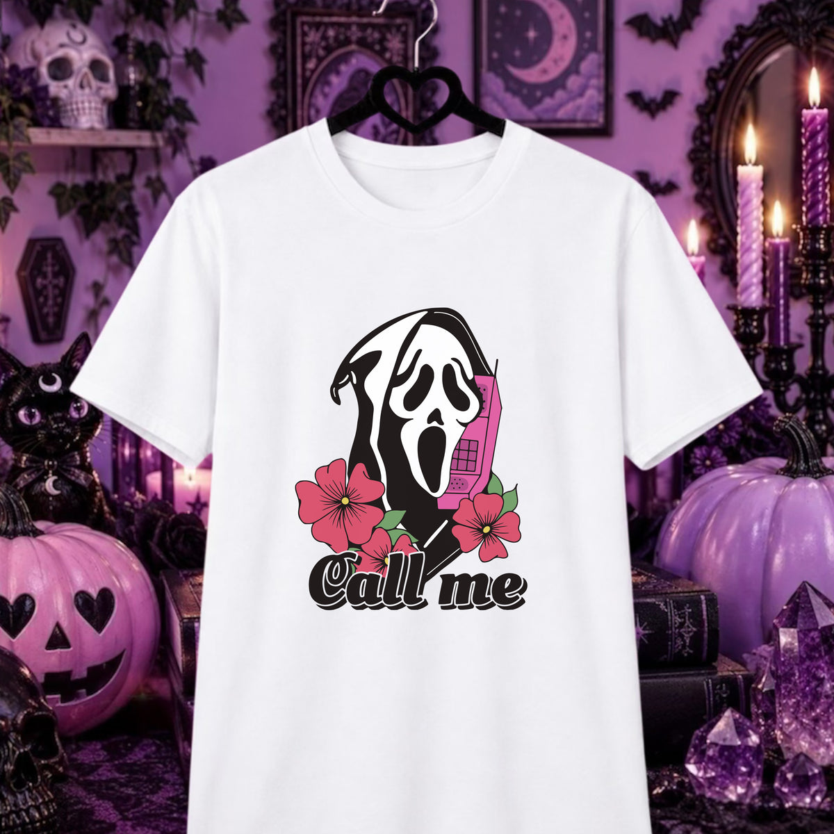 A white short-sleeve t-shirt hanging on a black hanger against a Halloween-themed purple background. The shirt features a graphic of the Ghostface character holding a pink phone, surrounded by pink flowers and the text 'Call me'.