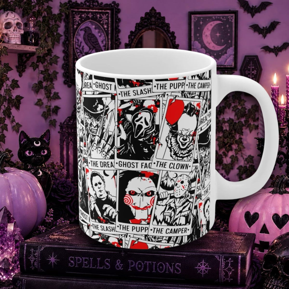 A white ceramic mug with a black and red comic-style horror collage print, displayed on a dark book surrounded by Halloween decorations like pumpkins, a black cat, and purple wall decor.