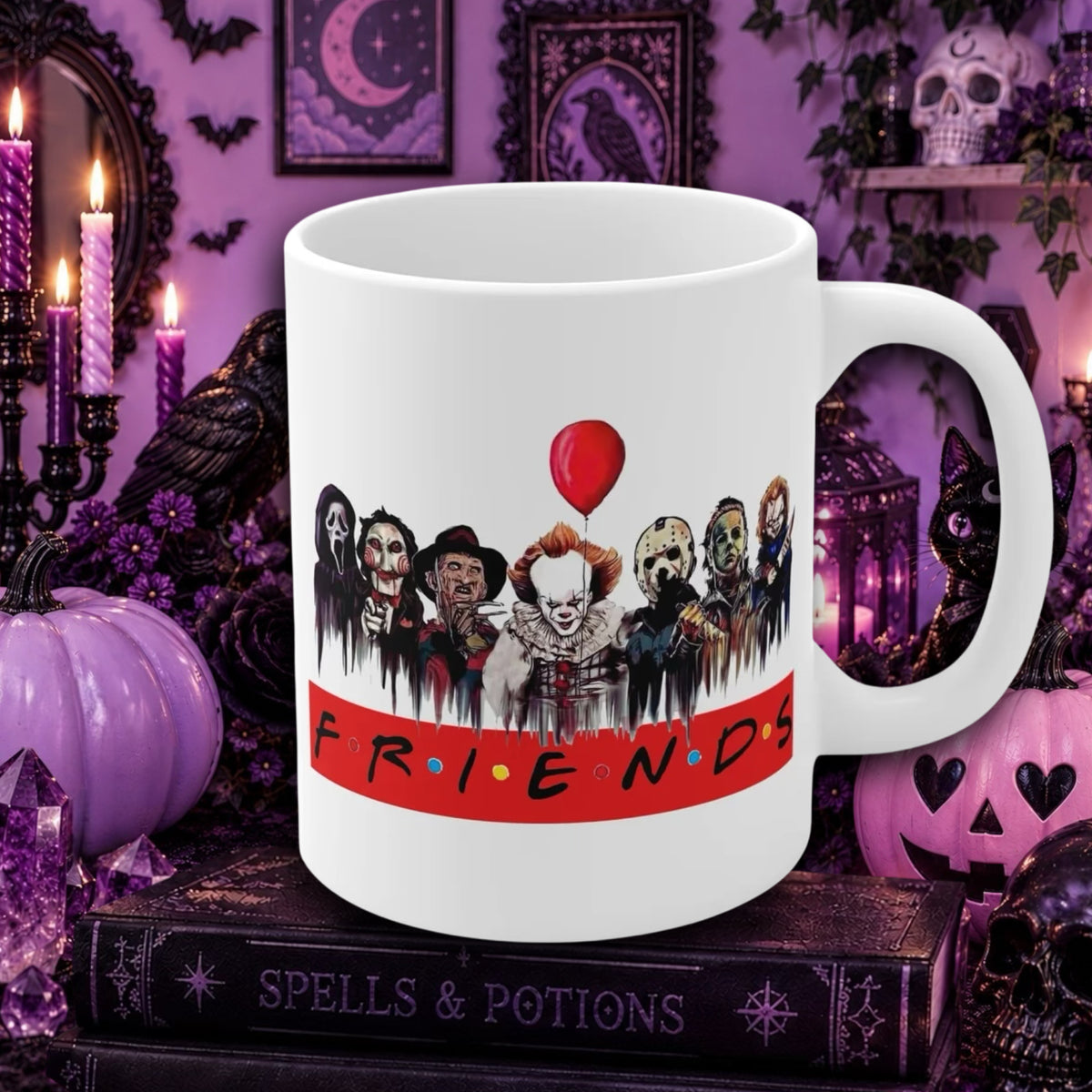 A white ceramic mug featuring a horror-themed graphic print with Pennywise and the word 'FRIENDS' on a red banner, set against a spooky purple Halloween background with candles, pumpkins, and books.