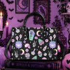 A black tote bag with a colorful gothic witch pattern featuring cauldrons, skulls, skeletons, and moons, displayed on a book in a purple Halloween-themed room.