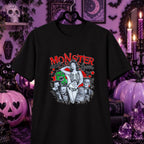 A black short-sleeve graphic T-shirt hanging on a black hanger against a Halloween-themed purple background. The shirt features a retro-style graphic with the text 'MONSTER Queen' in red, a skeleton figure, and illustrated horror characters in black, white, and green.