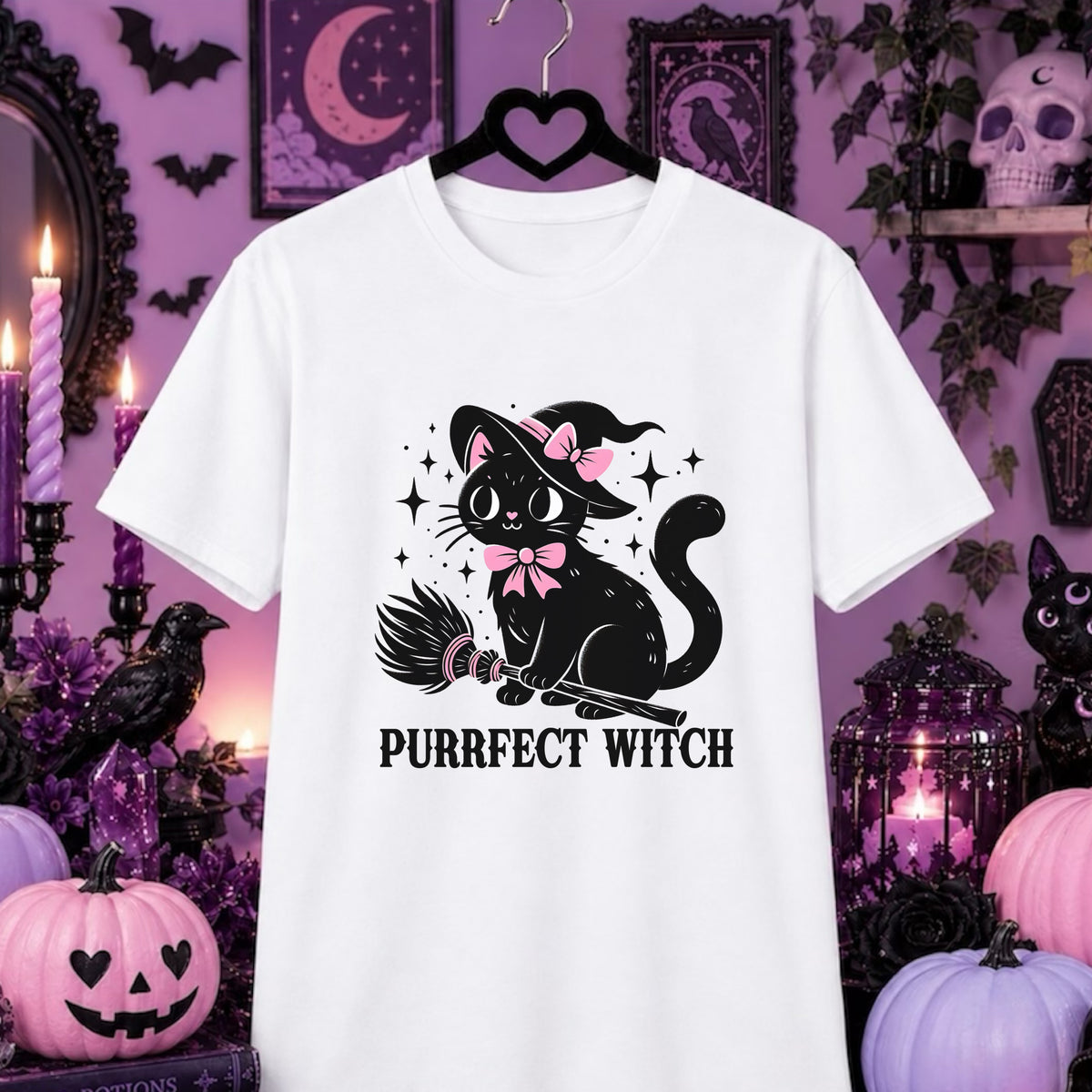 A white short-sleeve t-shirt on a black hanger, featuring a graphic of a black witch cat with a pink bow and hat riding a broomstick, with the text 'PURRFECT WITCH' below. The shirt is displayed against a purple Halloween-themed background with pumpkins, candles, and decorative items.