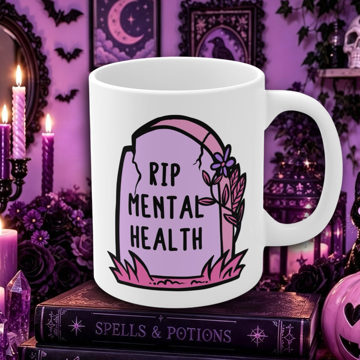 A white ceramic mug with a 'RIP MENTAL HEALTH' tombstone graphic, displayed on a book in a gothic, purple-themed setting with candles and occult decor.